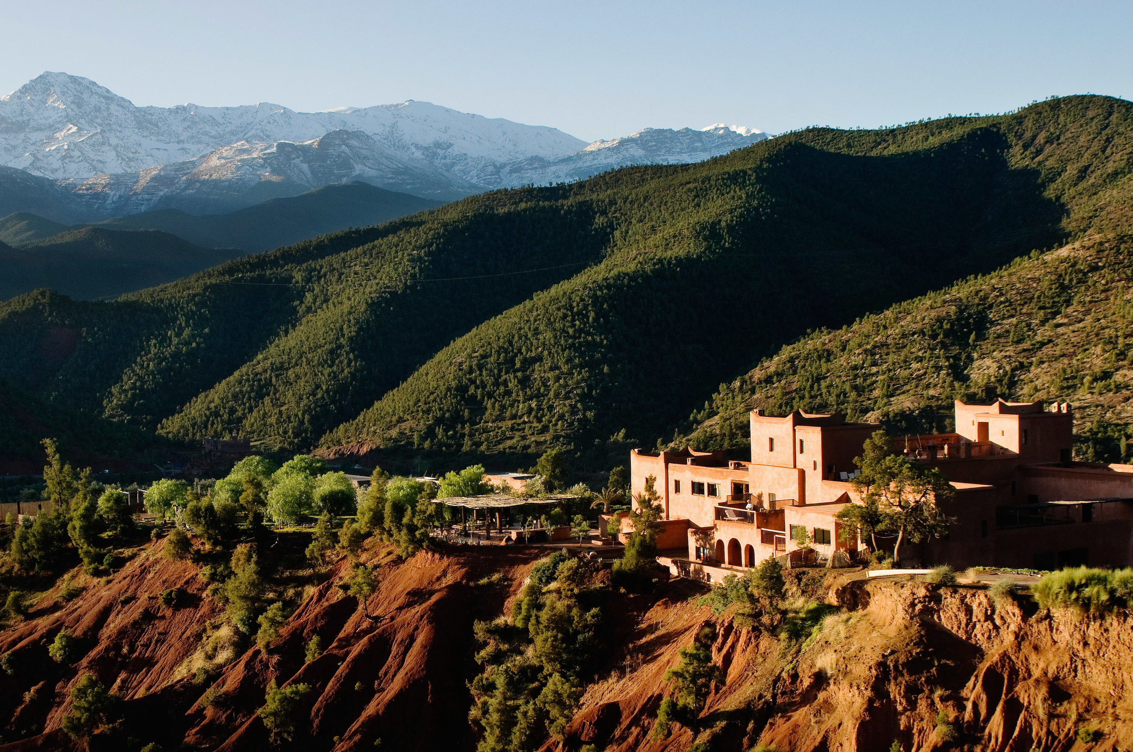 Terracotta buildings nestled in Oukaimden Valley with snow-capped High Atlas Mountains