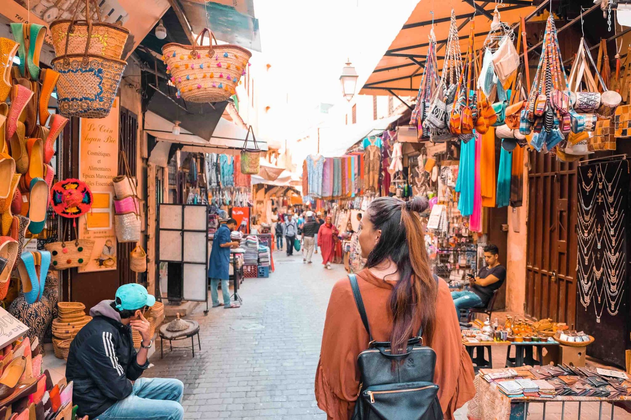Colorful Moroccan Marrakech market in the Medina with vibrant textiles, baskets, and tourists exploring