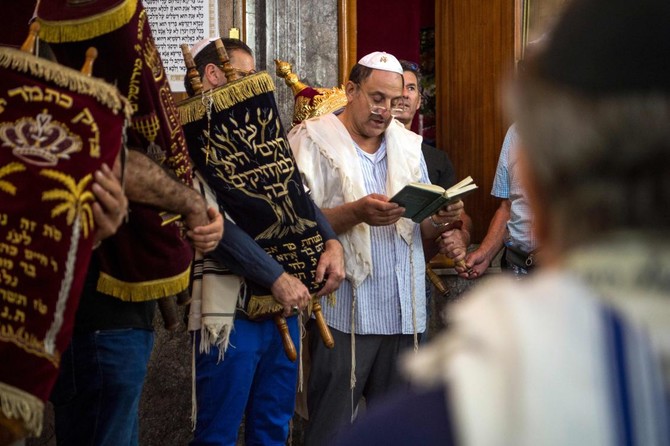 Jewish men reading from a prayer book and carrying a traditional Torah scroll during a Jewish heritage trip in Morocco by Moroccan Guides Travel.