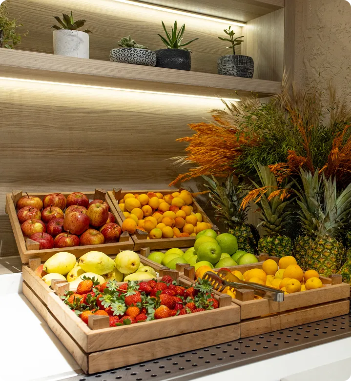 Wooden crates filled with apples, apricots, pineapples, green apples, pears, and strawberries on a countertop.