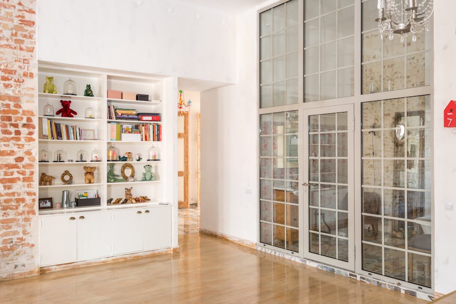 Bright interior room with floor-to-ceiling glass doors and decorative shelves.