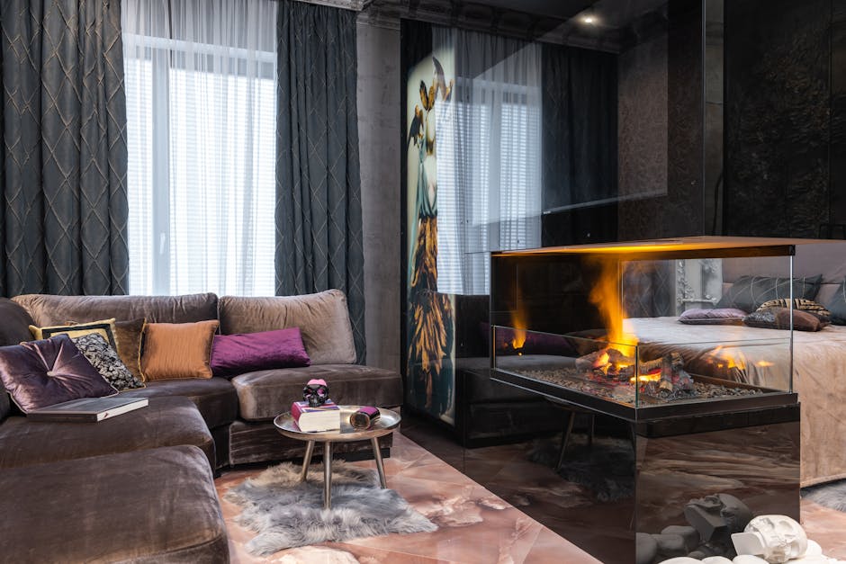 Interior of modern apartment with comfortable couch and side table with decorations placed near burning fireplace at bed in stylish room