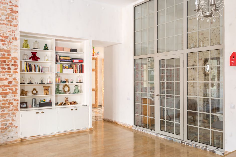 Bright interior room with floor-to-ceiling glass doors and decorative shelves.