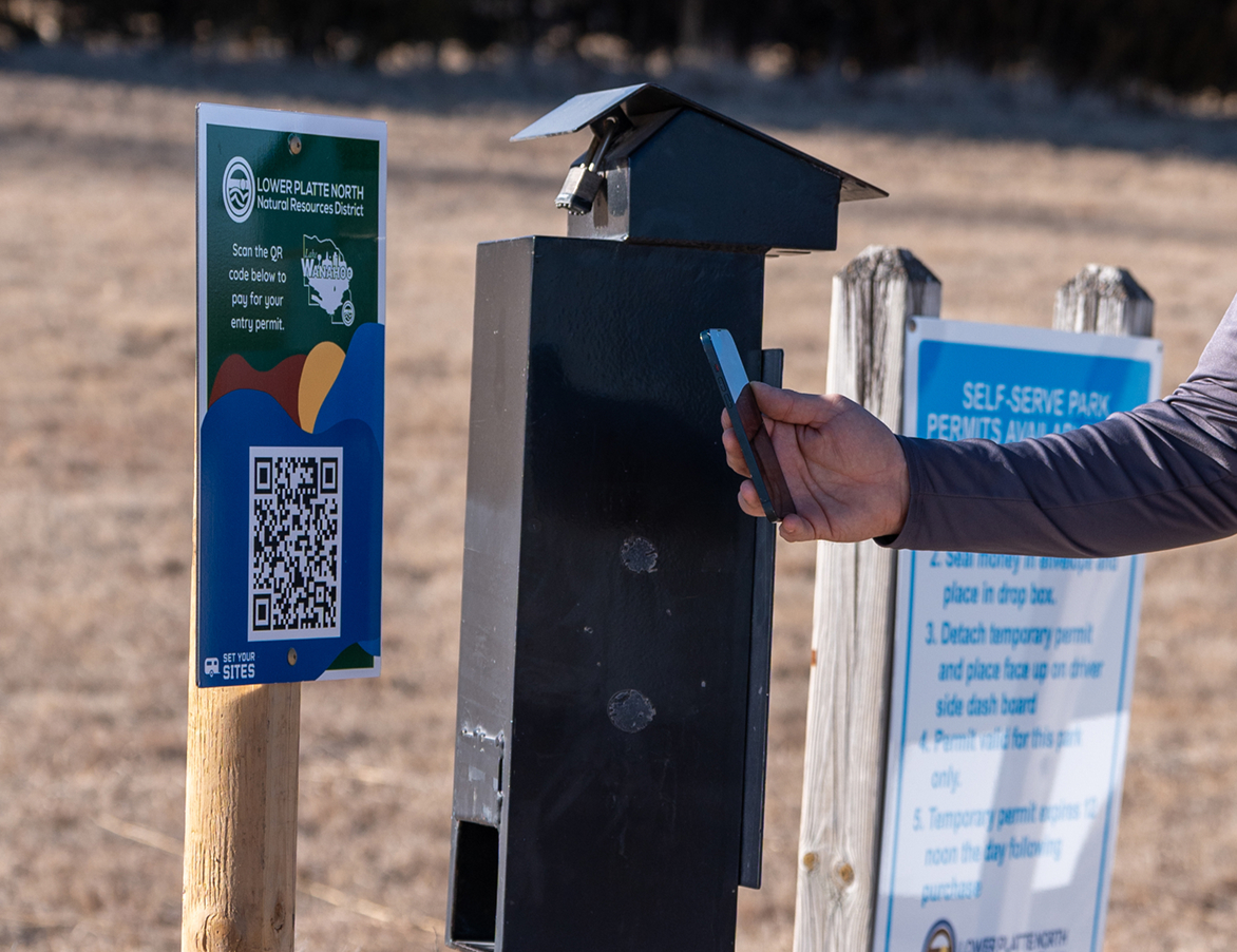 person holding phone up to QR code to pay for campsite