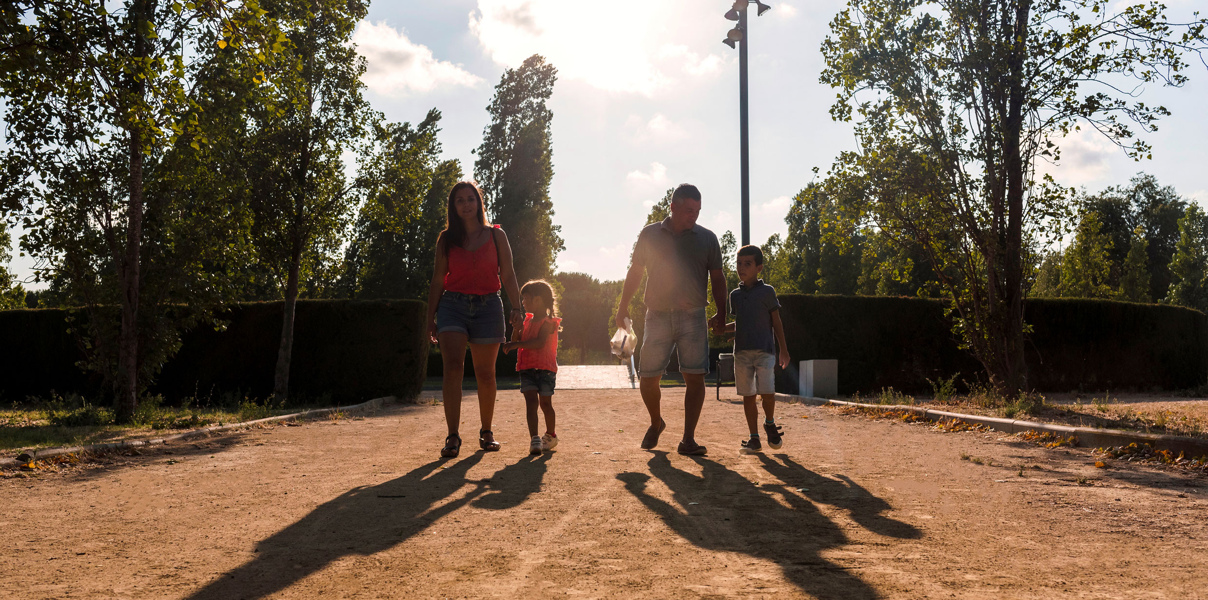 Family of four walking into campground at sunrise.