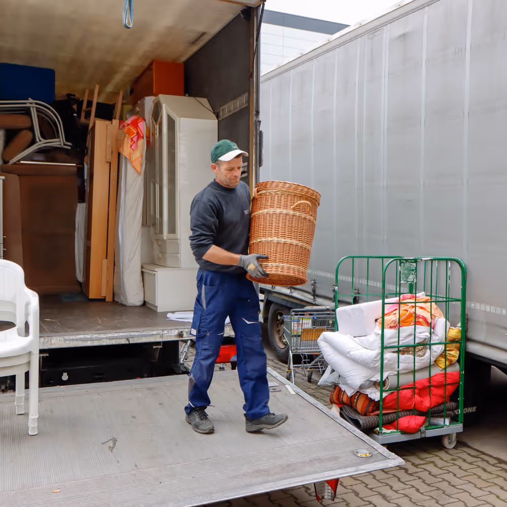 GRAVITAS Mitarbeiter bei einer Wohnungsauflösung, Entrümpelung oder Kleintransporter Seniorenumzug räumt Korb aus dem Lieferwagen aus.
