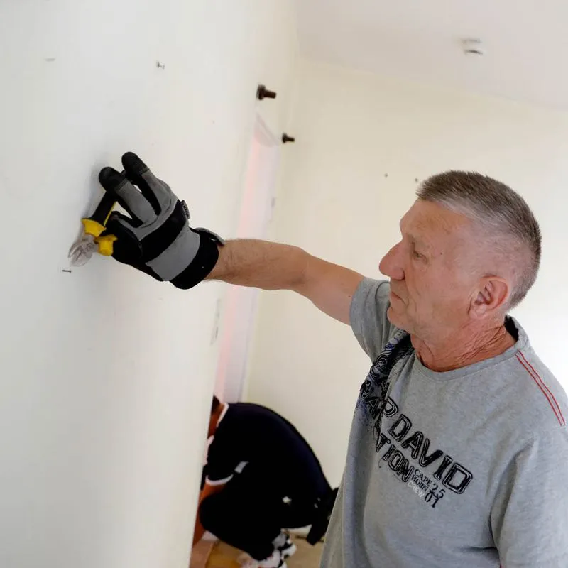 Herr Andrija Blazevic entfernt mit Werkzeug eine Befestigung aus der Wand bei einer professionellen Räumung.