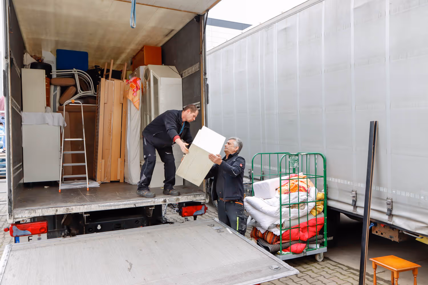 GRAVITAS Mitarbeiter bei einem Kleintransporter Seniorenumzug räumt Gestell aus dem Lieferwagen.