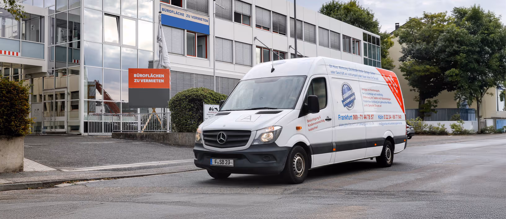 Mitarbeiter von GRAVITAS führen eine professionelle Firmenauflösung und Entrümpelung durch. Auf den Bild ist der GRAVITAS Transporter vor einem Firmengebäude zu sehen.