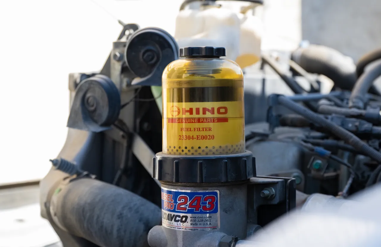Heavy-duty fuel filter installed on a truck engine shows Hino Genuine Parts Fuel Filter 23304-E0020 and DAVCO Fuel Pro 243.