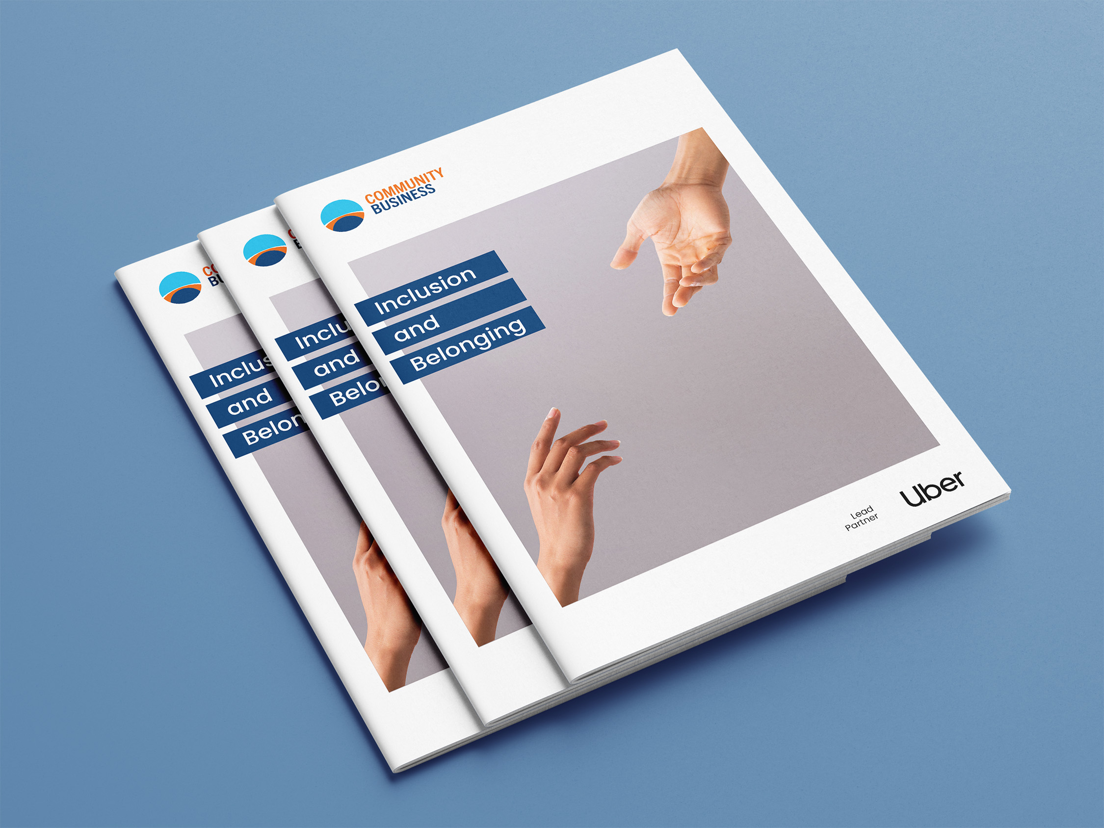 Three stacked brochures titled 'Inclusion and Belonging' with Community Business logo and Uber as lead partner, showing two hands reaching toward each other.