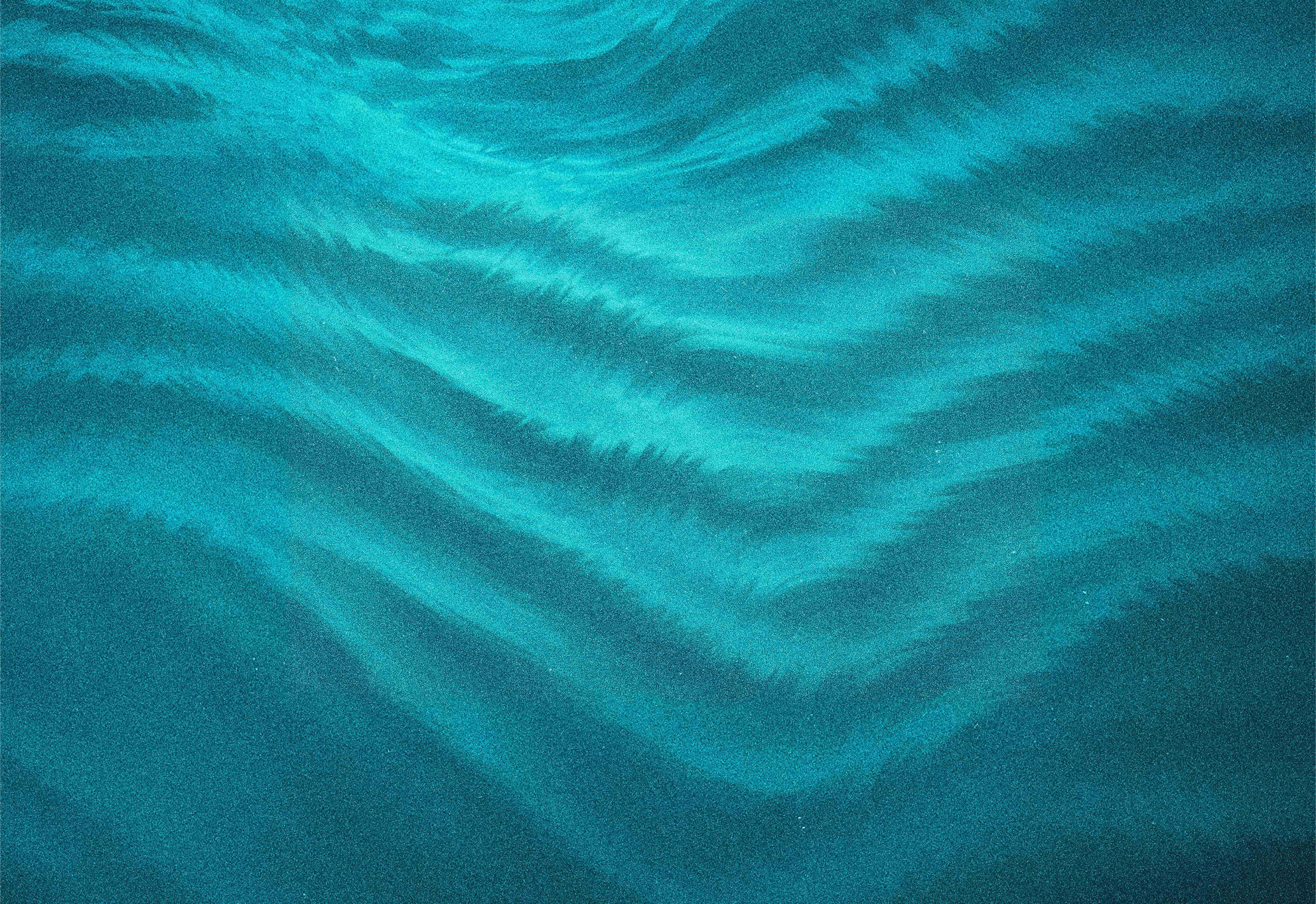 Teal-colored textured surface with wave-like flowing patterns resembling fabric or water ripples.