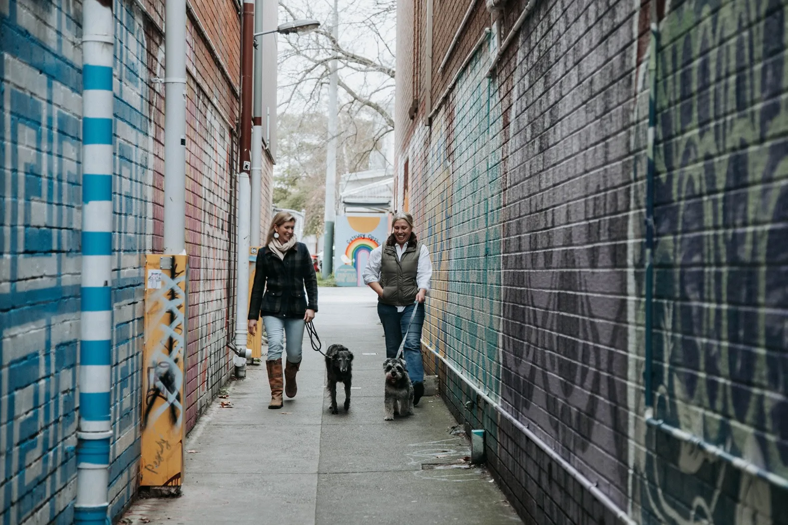 Nicole and Nat walking with two dogs outdoors.