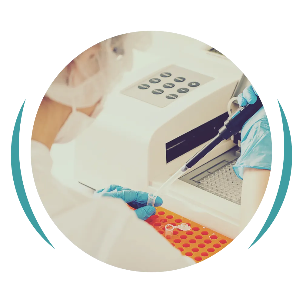 Lab technician pipetting samples into test tubes beside an analyser machine.