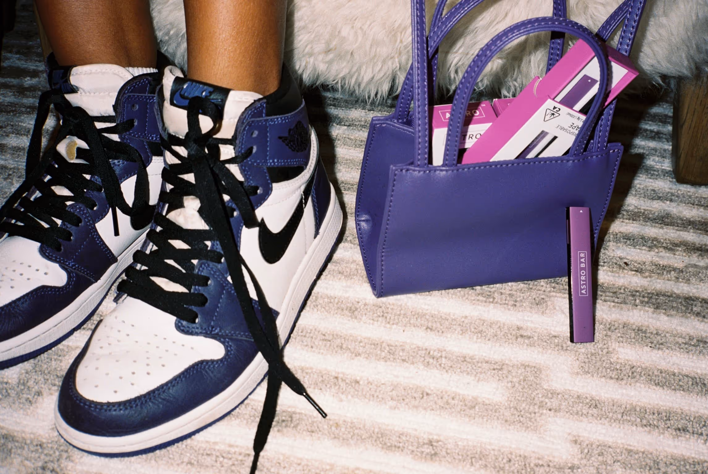 A pair of sneakers and a purple purse.