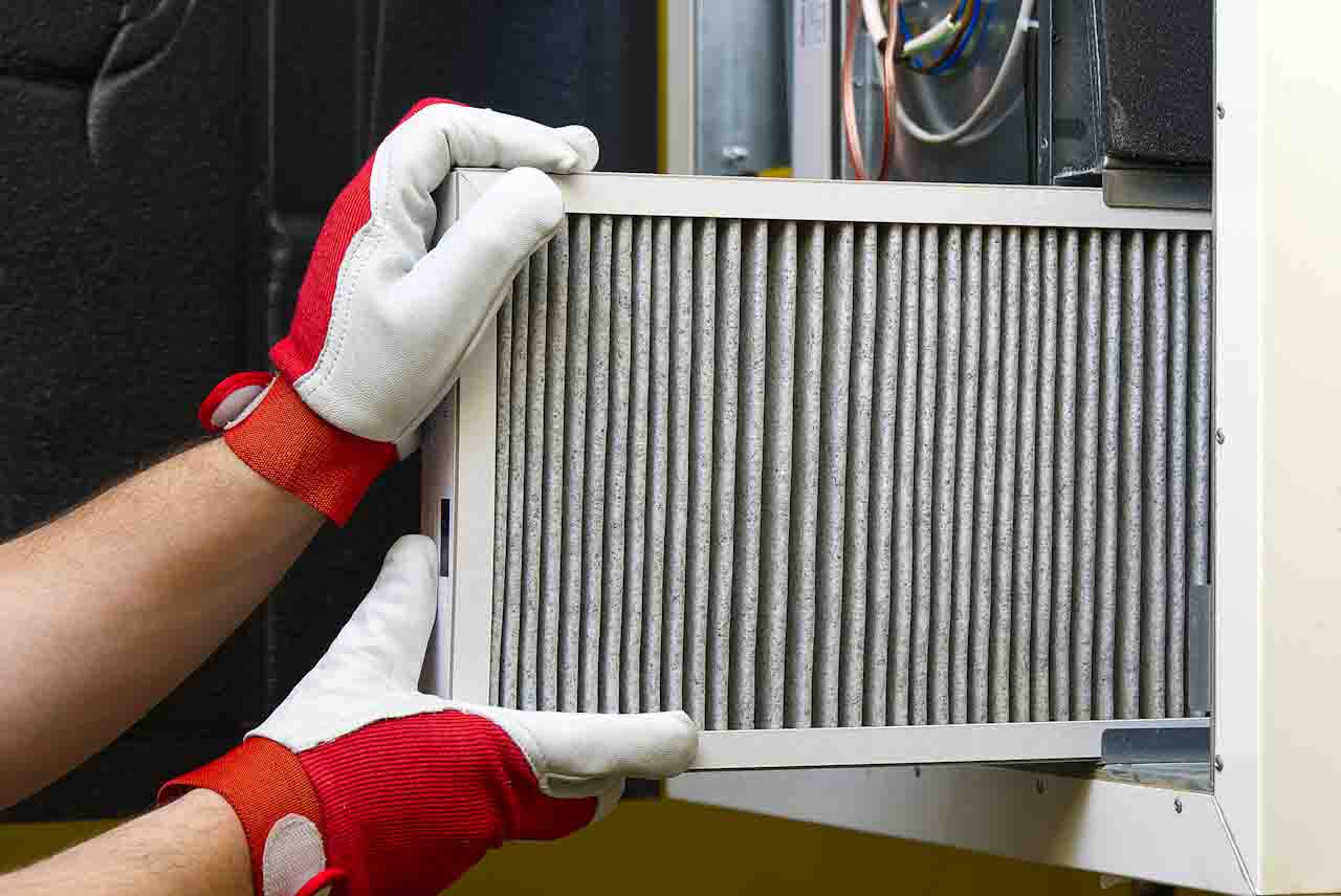A pair of hands replacing a filter from a central air conditioning system.