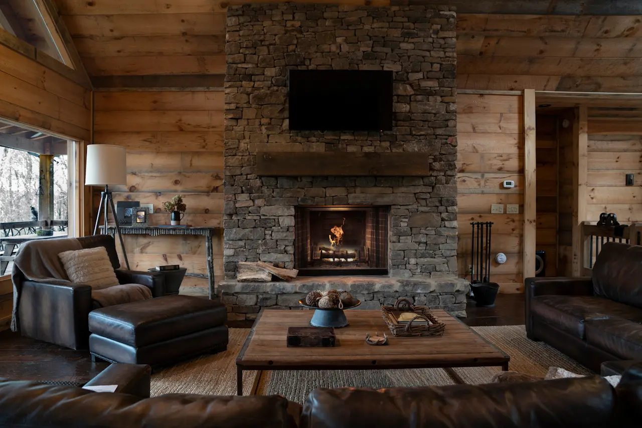 A living room with wood walls and ceiling, a brick fireplace, and a tv above the fireplace.