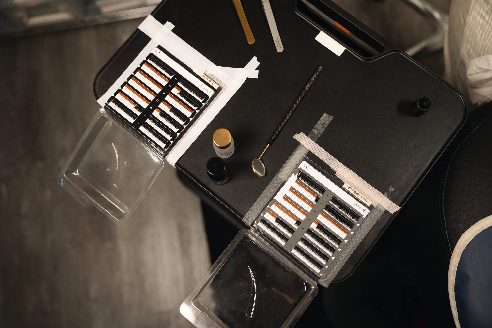 Lash extension trays and tools laid out on a black tray