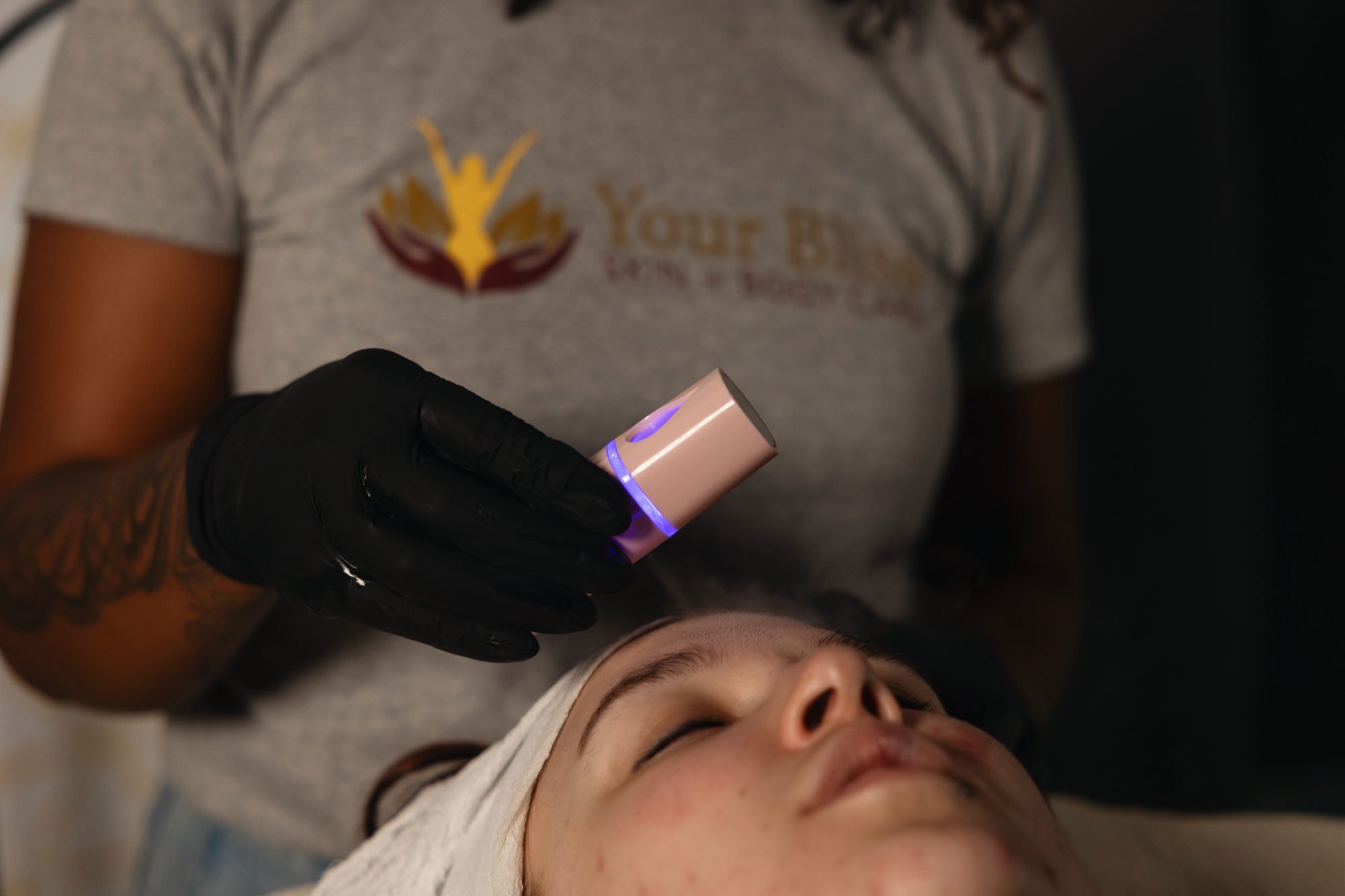 High frequency wand with a violet glow used on a client's forehead
