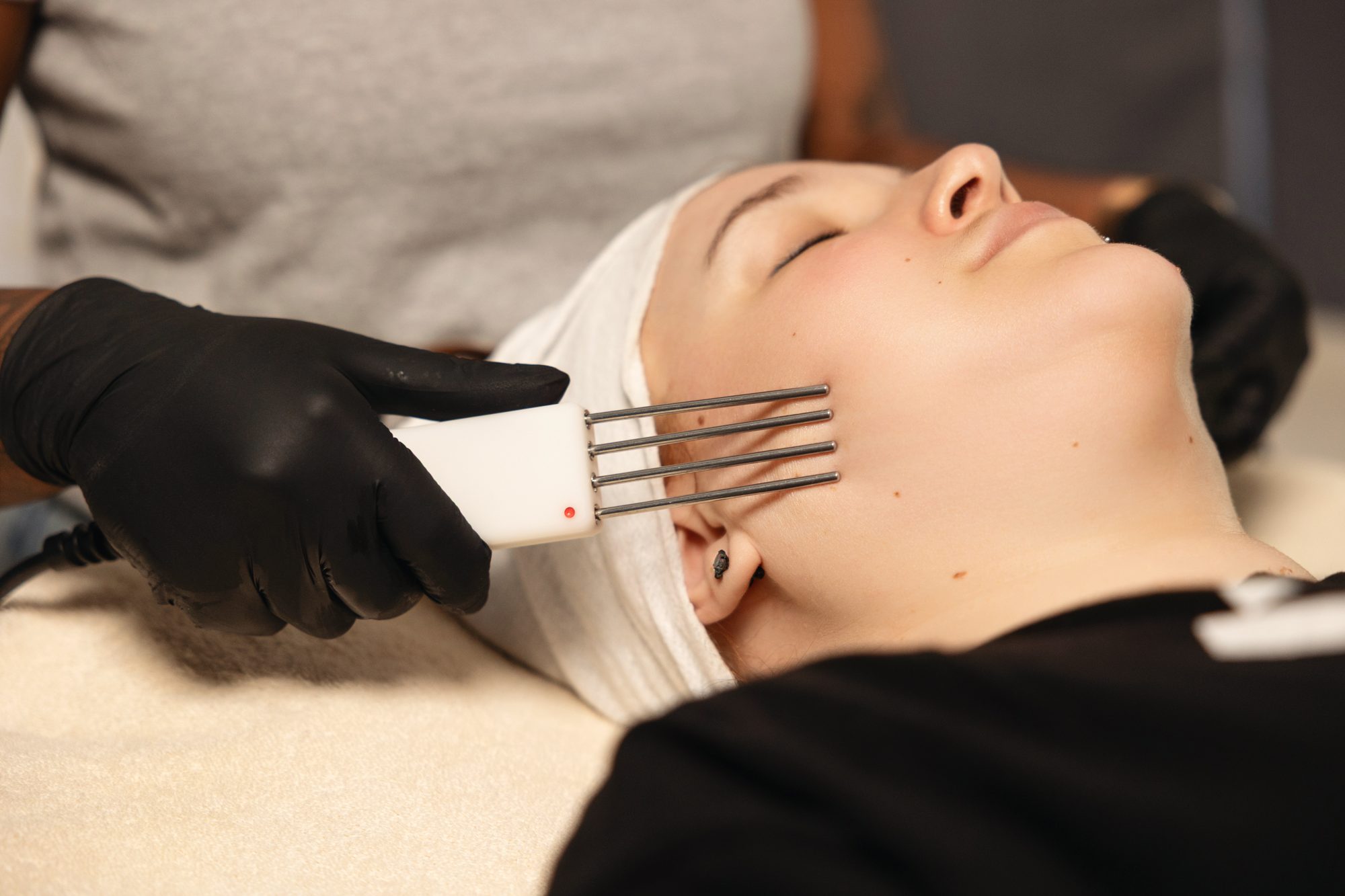 Microcurrent wand moving along a client's cheek