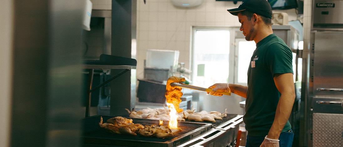 Cook holds chicken over grill