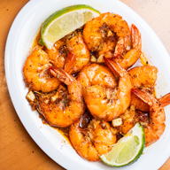 Close-up of shrimp on a plate with lime wedges.