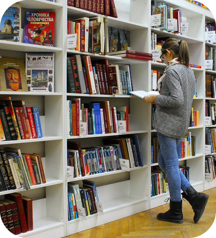Una chica de colegio leyendo un libro en la biblioteca.
