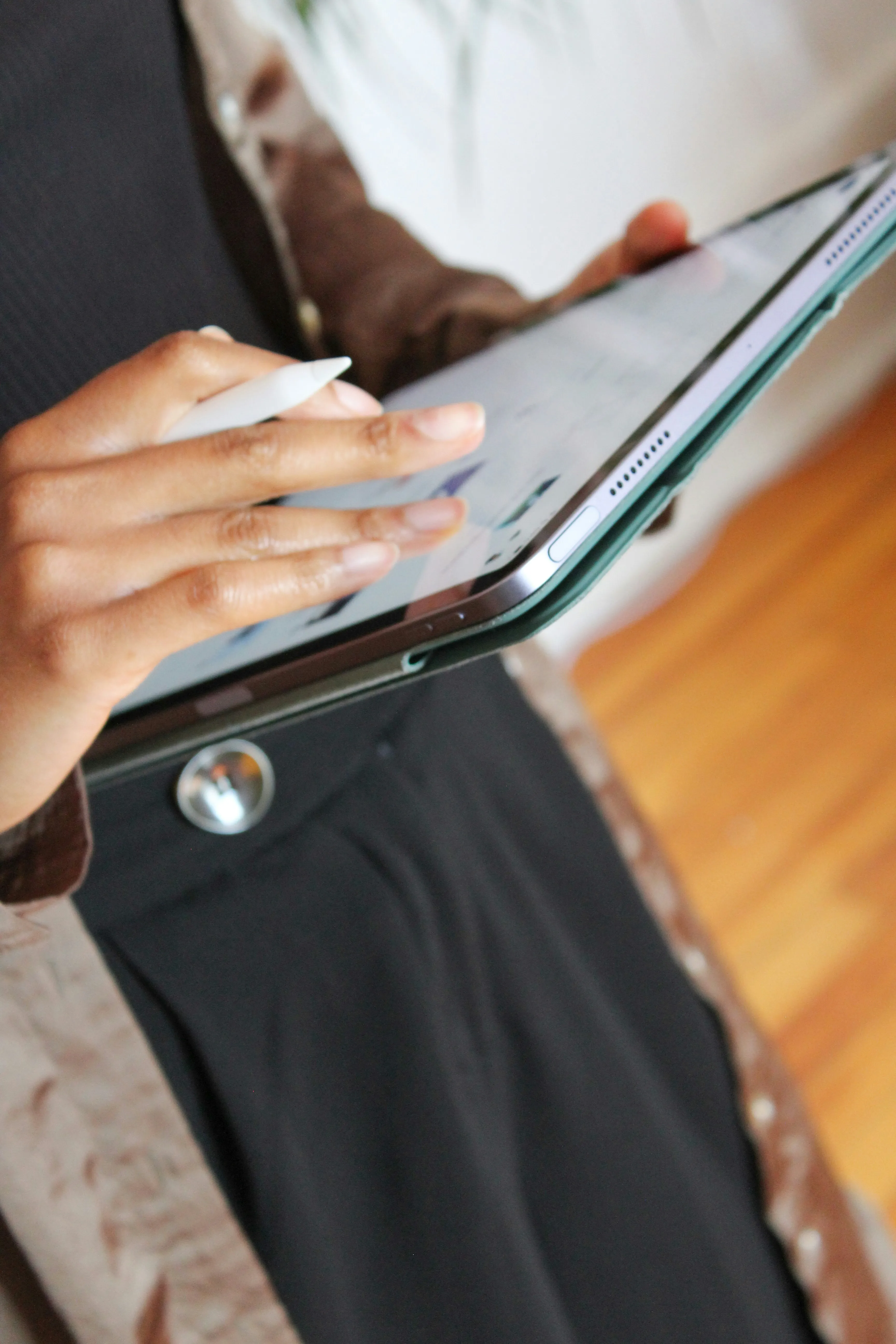 Person using a stylus pen on a tablet with a green case.