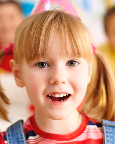 A little girl with pigtails smiling.