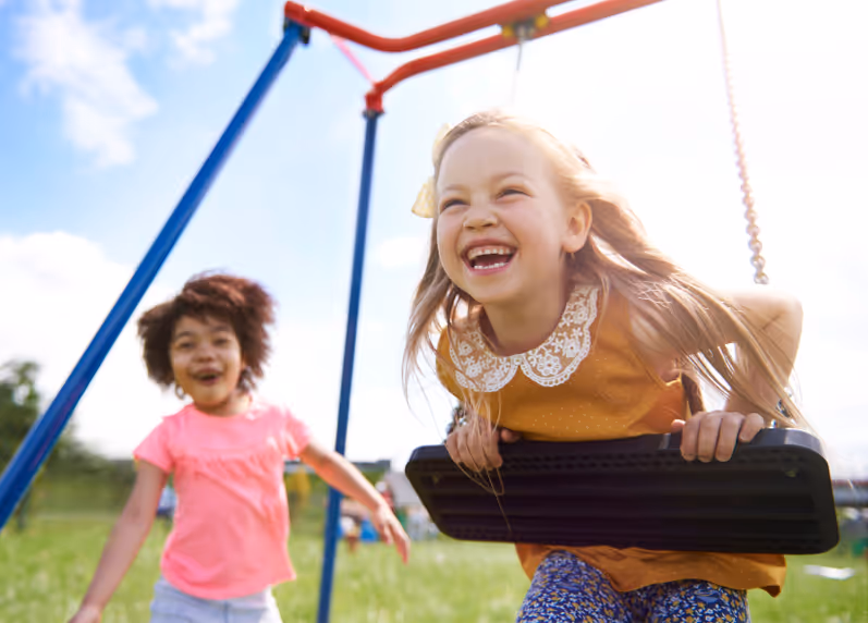 Two girls playing on a swingset.