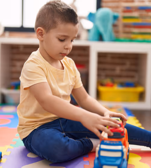 A little boy playing with a toy in a playroom.