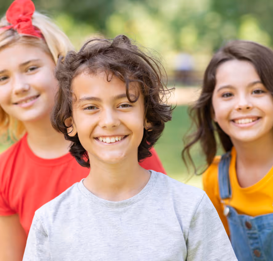 Three children smiling into the camera.