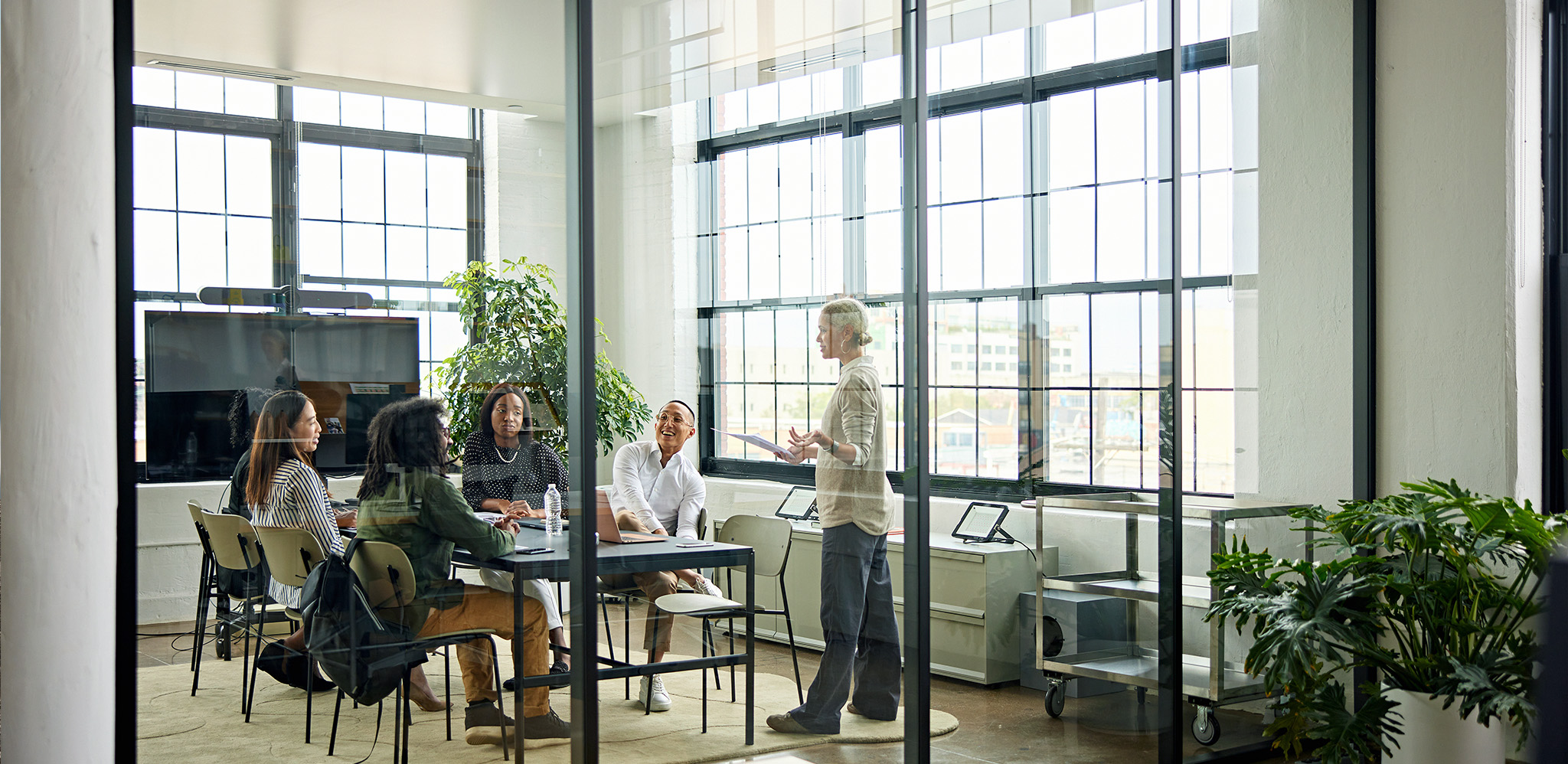 A female wealth management marketing expert conducting a meeting in a modern glass conference room discussing advisor growth strategy