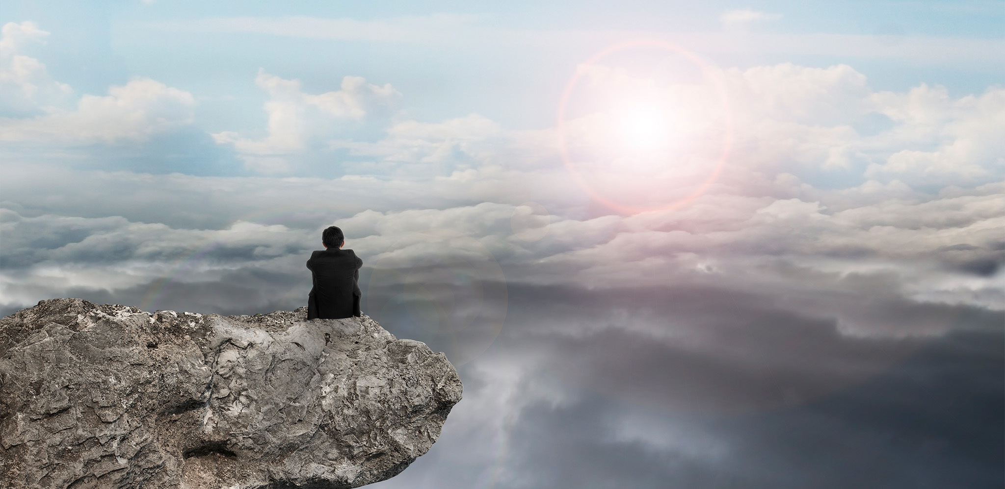 Man on rock looking at horizon contemplating advisor growth strategy help, wealth management marketing and family office consulting