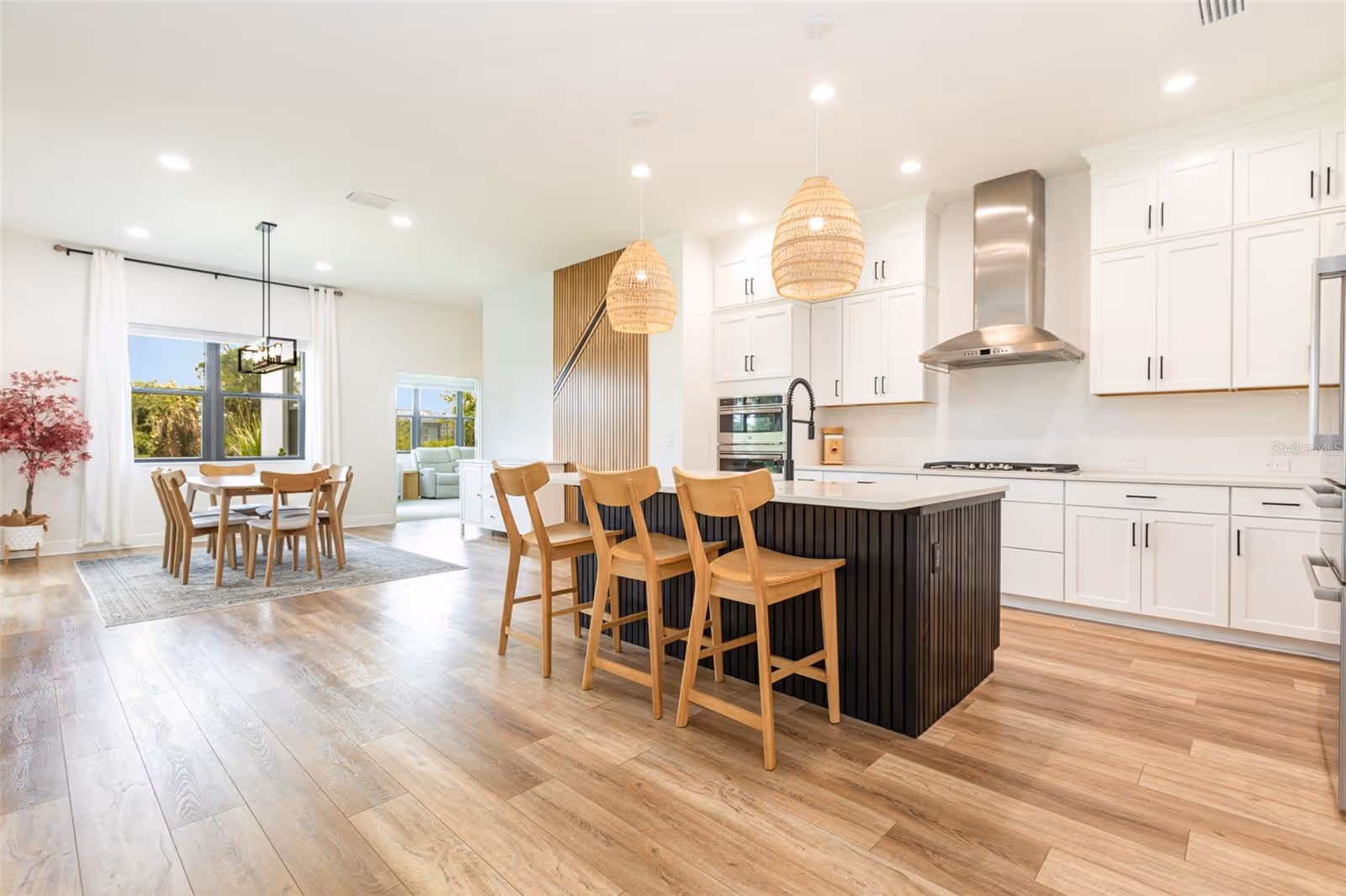 Bright modern kitchen with island, bar stools, dining table, and pendant lights in a stylish Sarasota waterfront home.