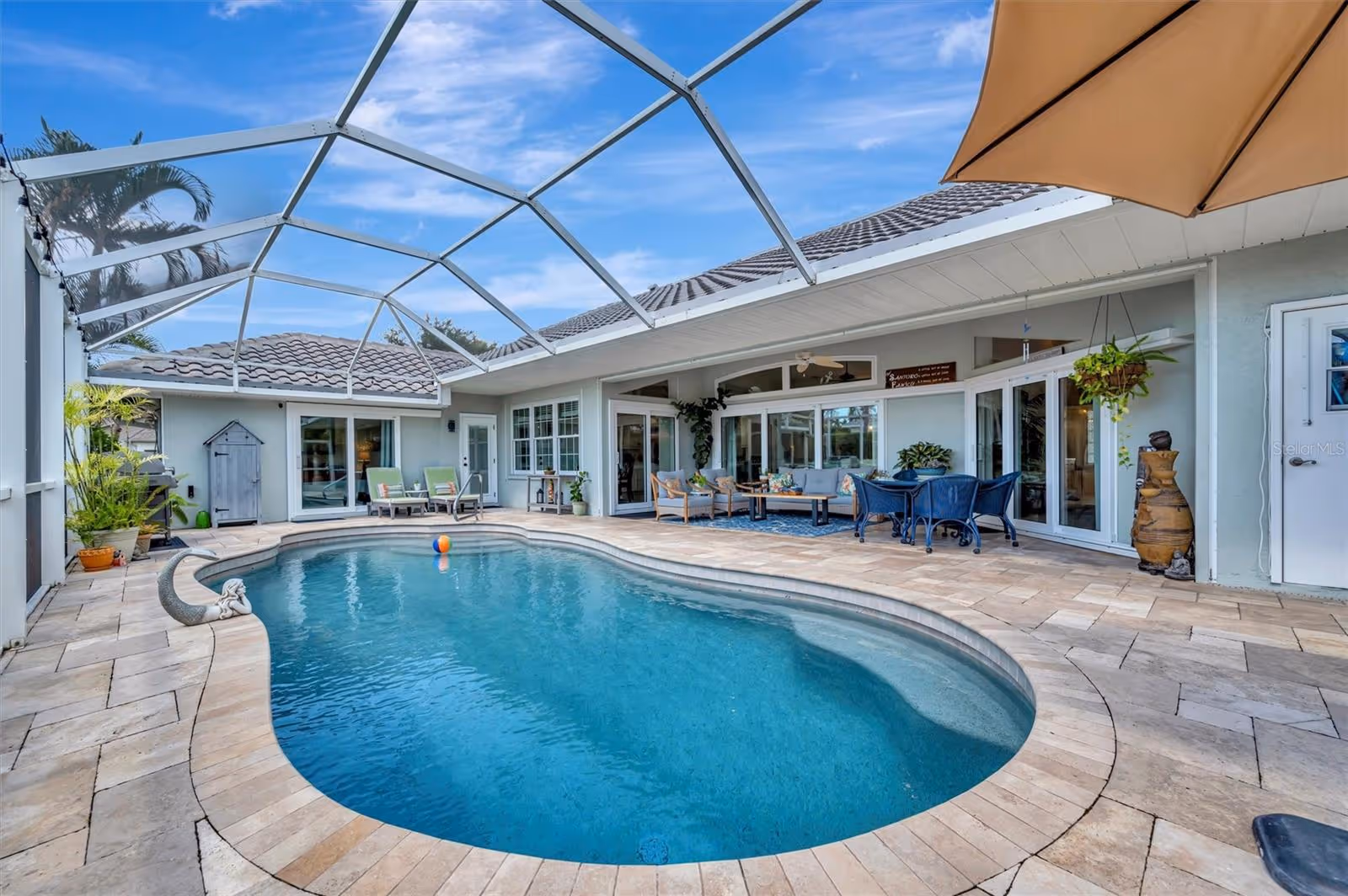 Relaxing backyard with swimming pool, patio furniture, umbrella, and decorative plants for outdoor living and leisure ideas.