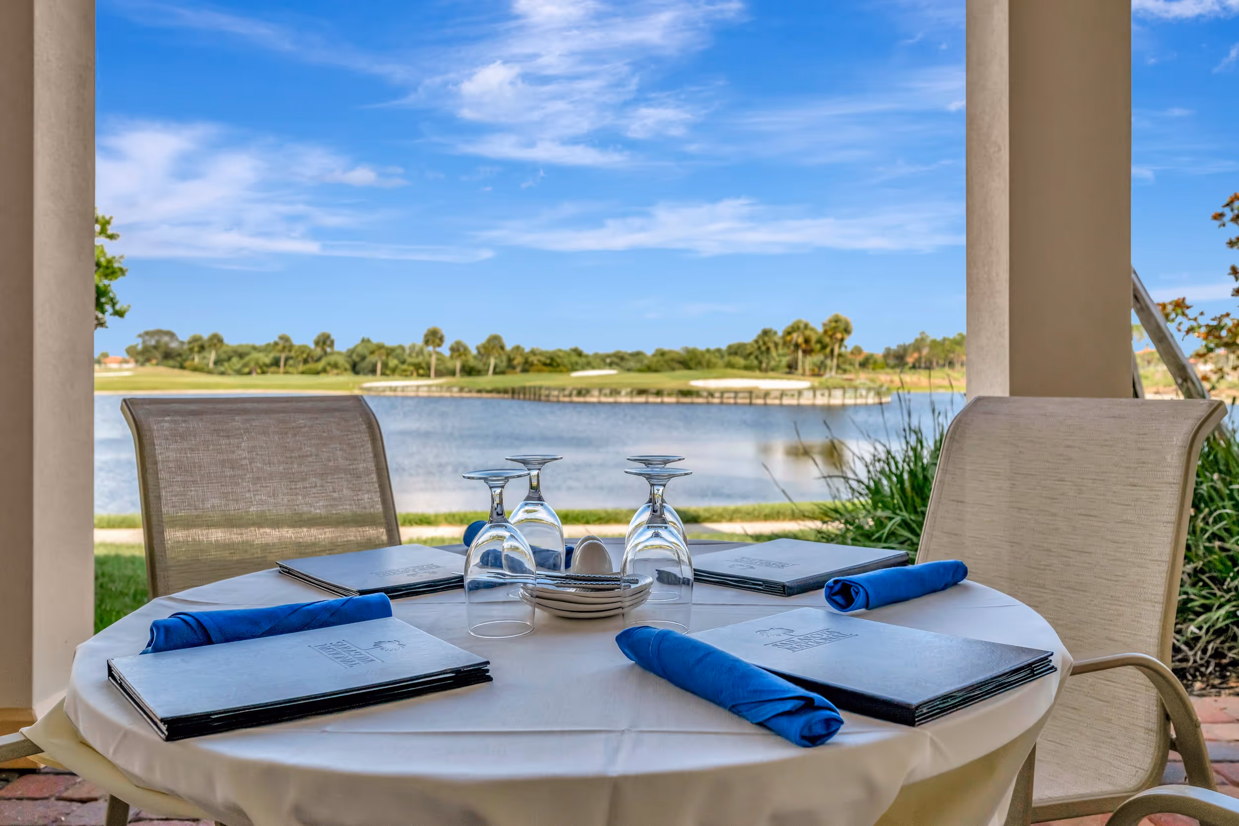 Golf course view of peaceful suburban neighborhood with lakefront homes, palm trees, and lawns in Sarasota real estate market.