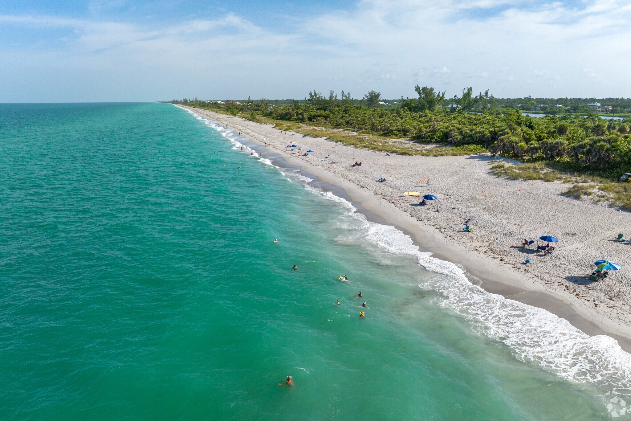 Sunny beach with turquoise water, families swimming and sunbathing, perfect for a relaxing beach vacation and family day.