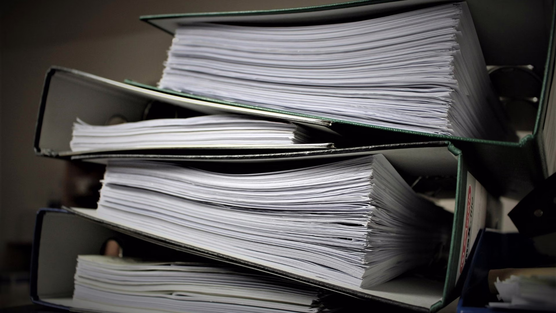 A stack of binders almost overflowing with paper