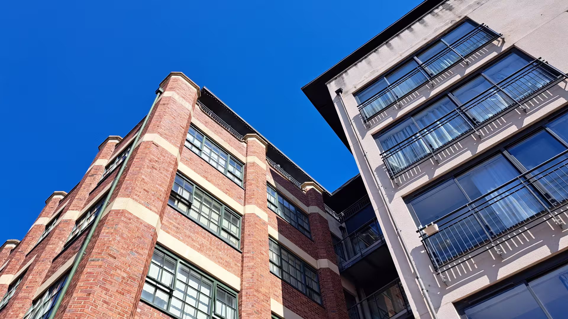 two apartment buildings, one red brick, one concrete