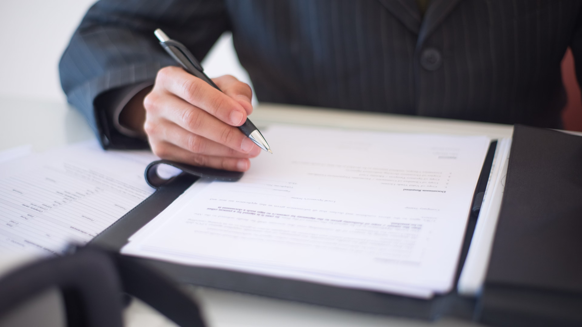 a person sitting at a desk signing a document