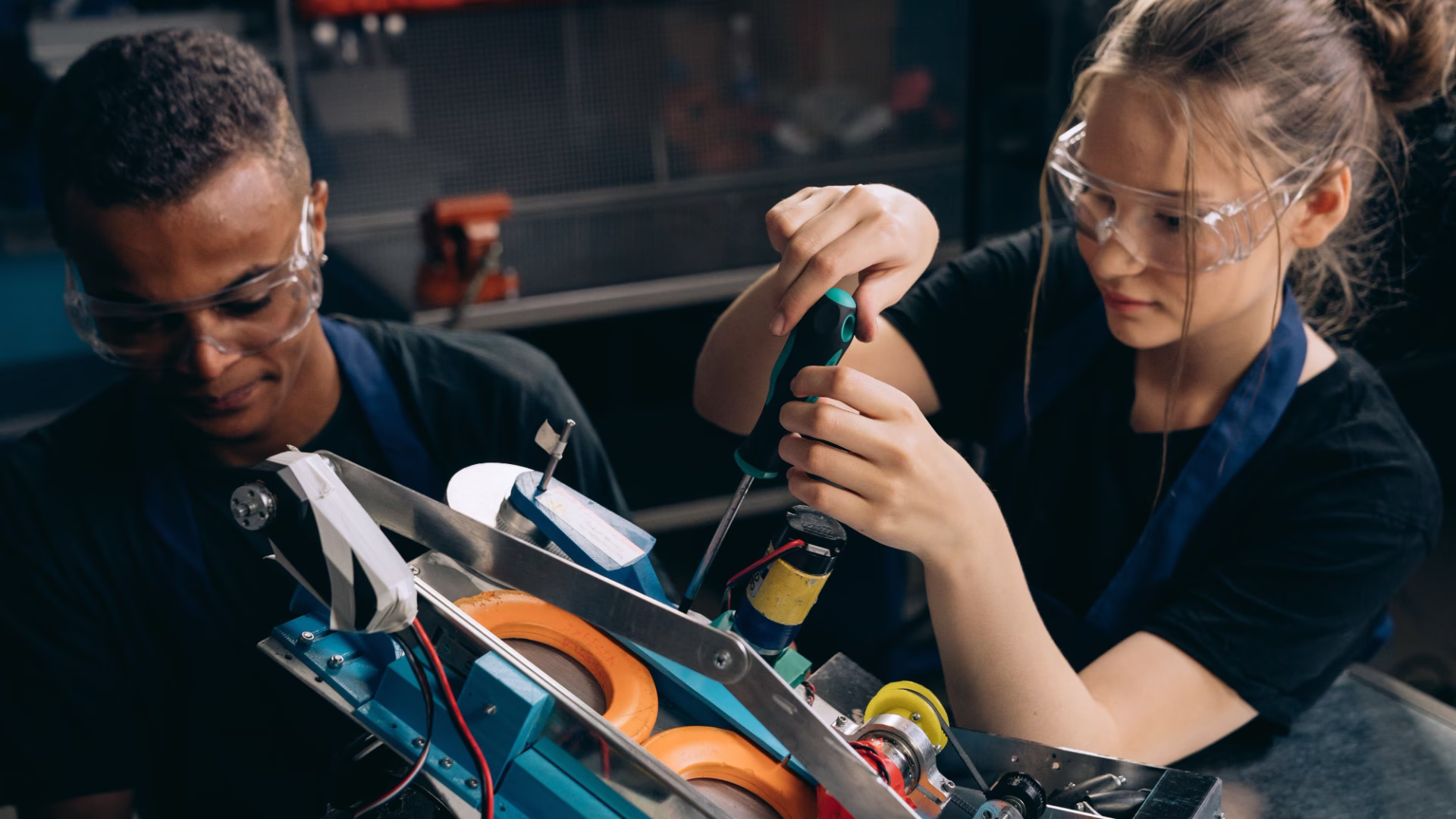 2 people with safety glasses on working to fix a machine