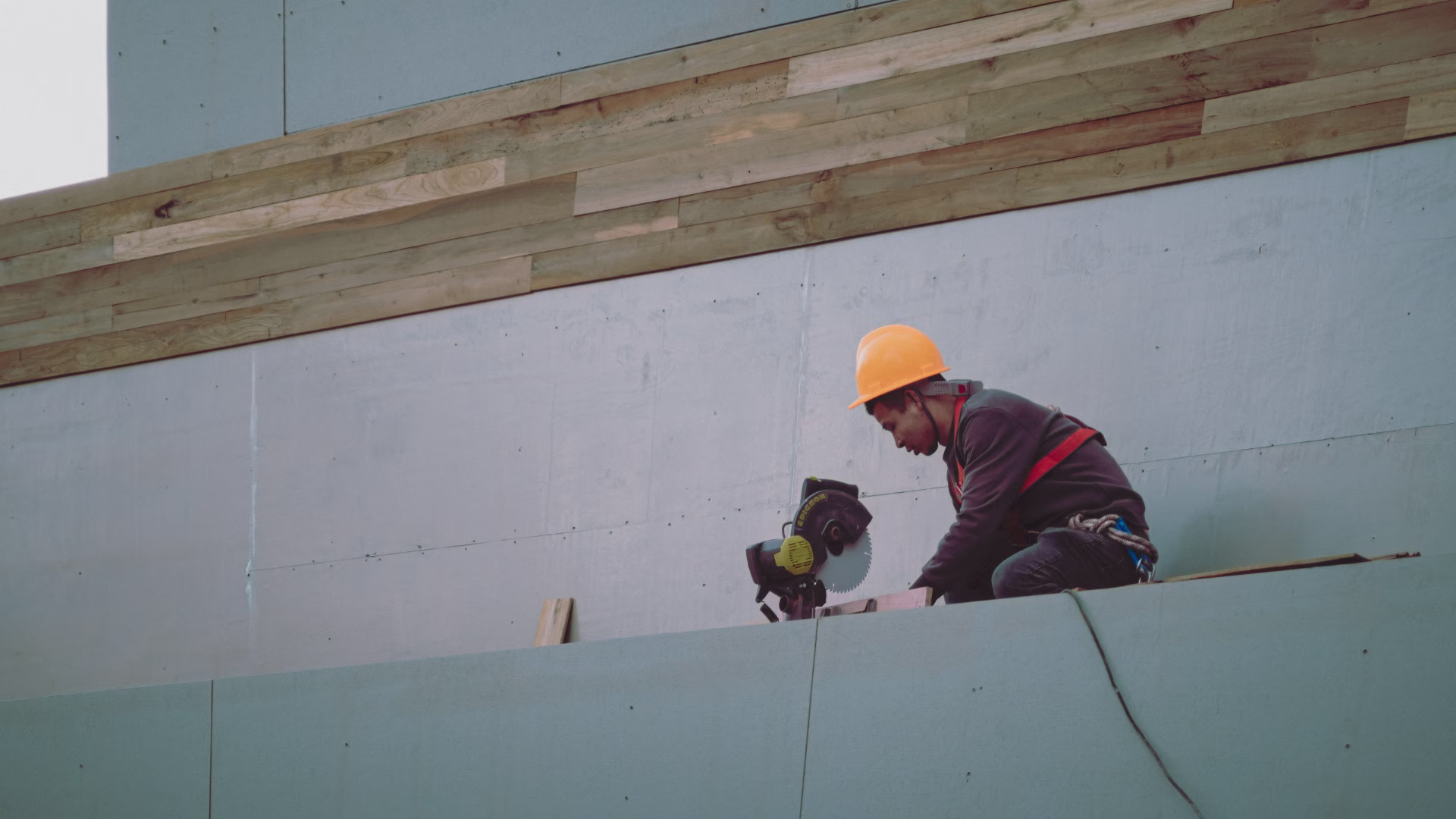 A contractor sitting on a ledge with a saw power tool