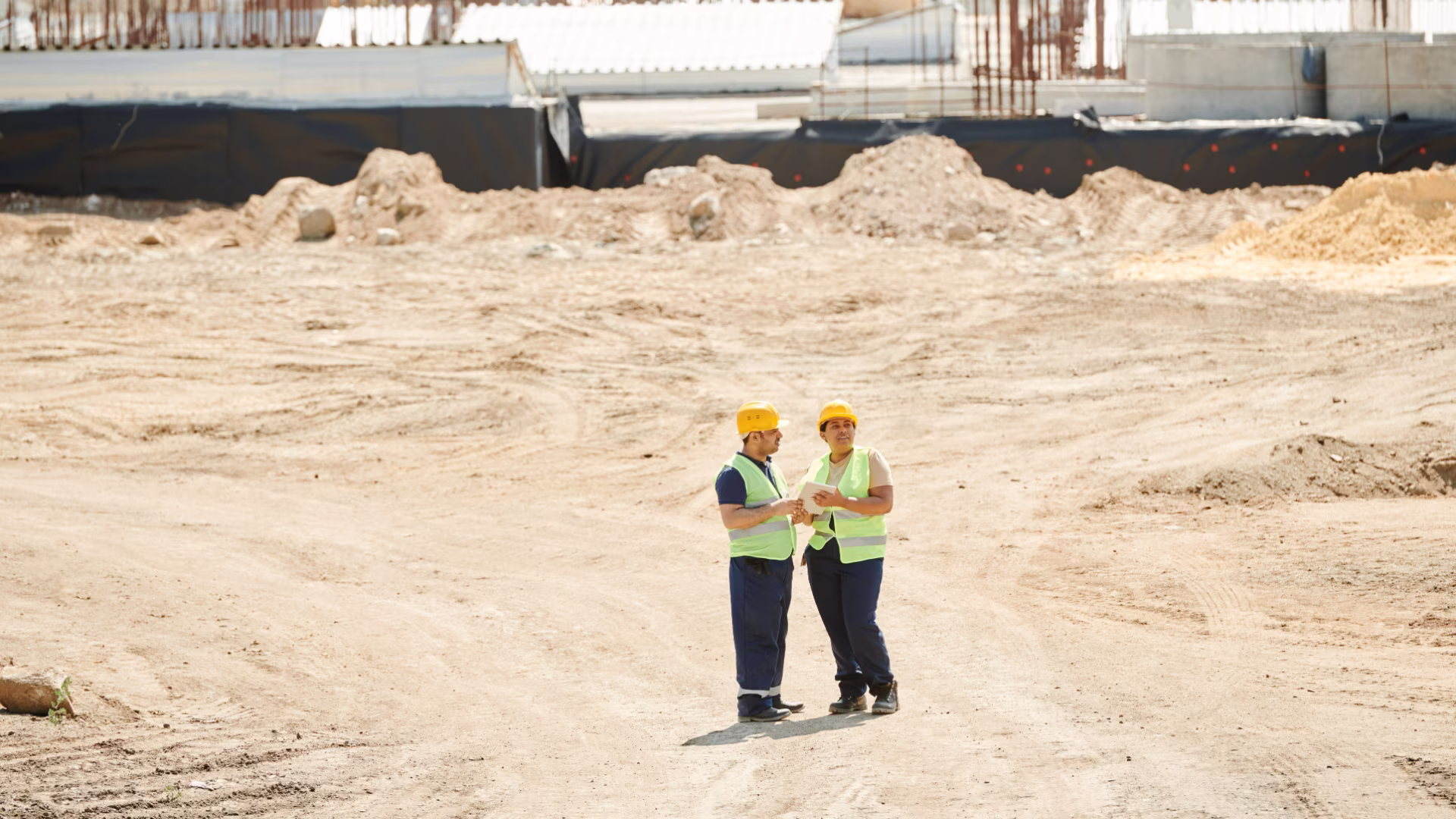 2 construction workers overlooking a job site from a distance