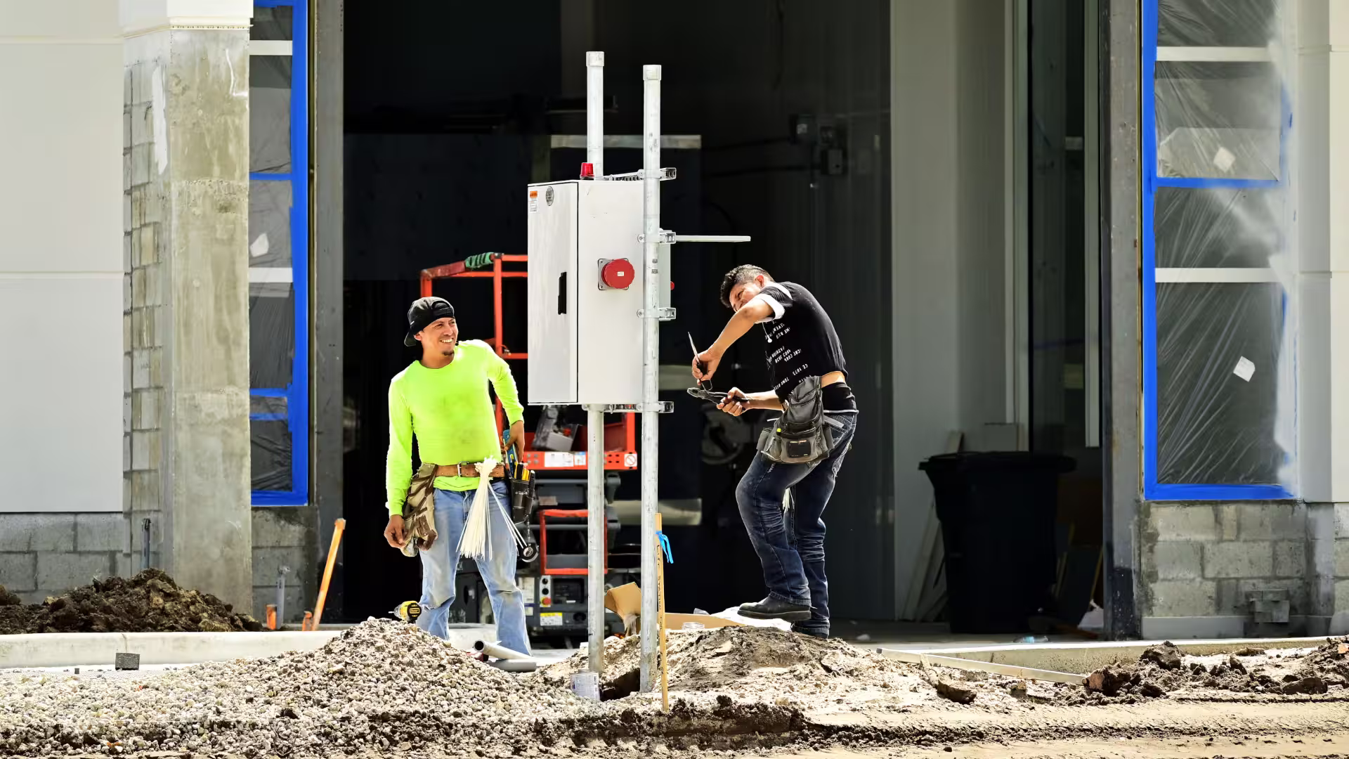 2 electricians working on a panel at a job site