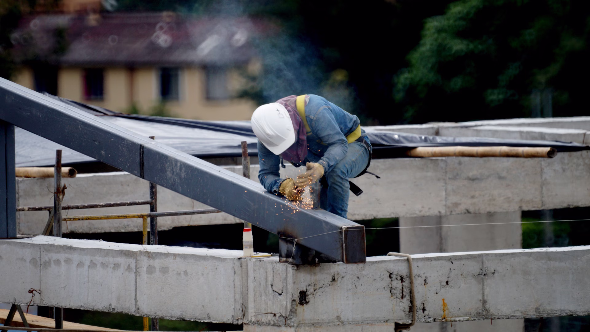 A construction worker on top of an unfinished building using a welder