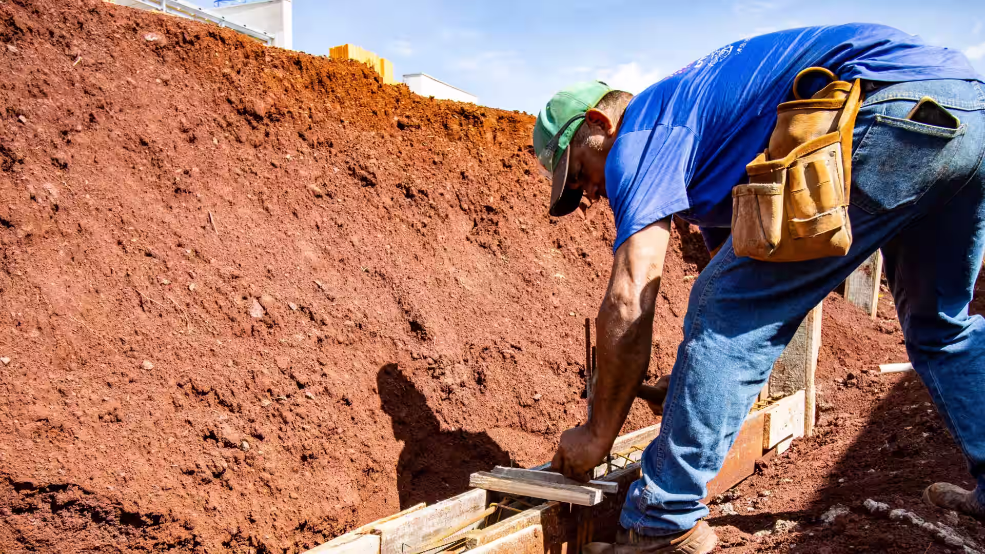 A construction vendor hammering a nail into wood foundation