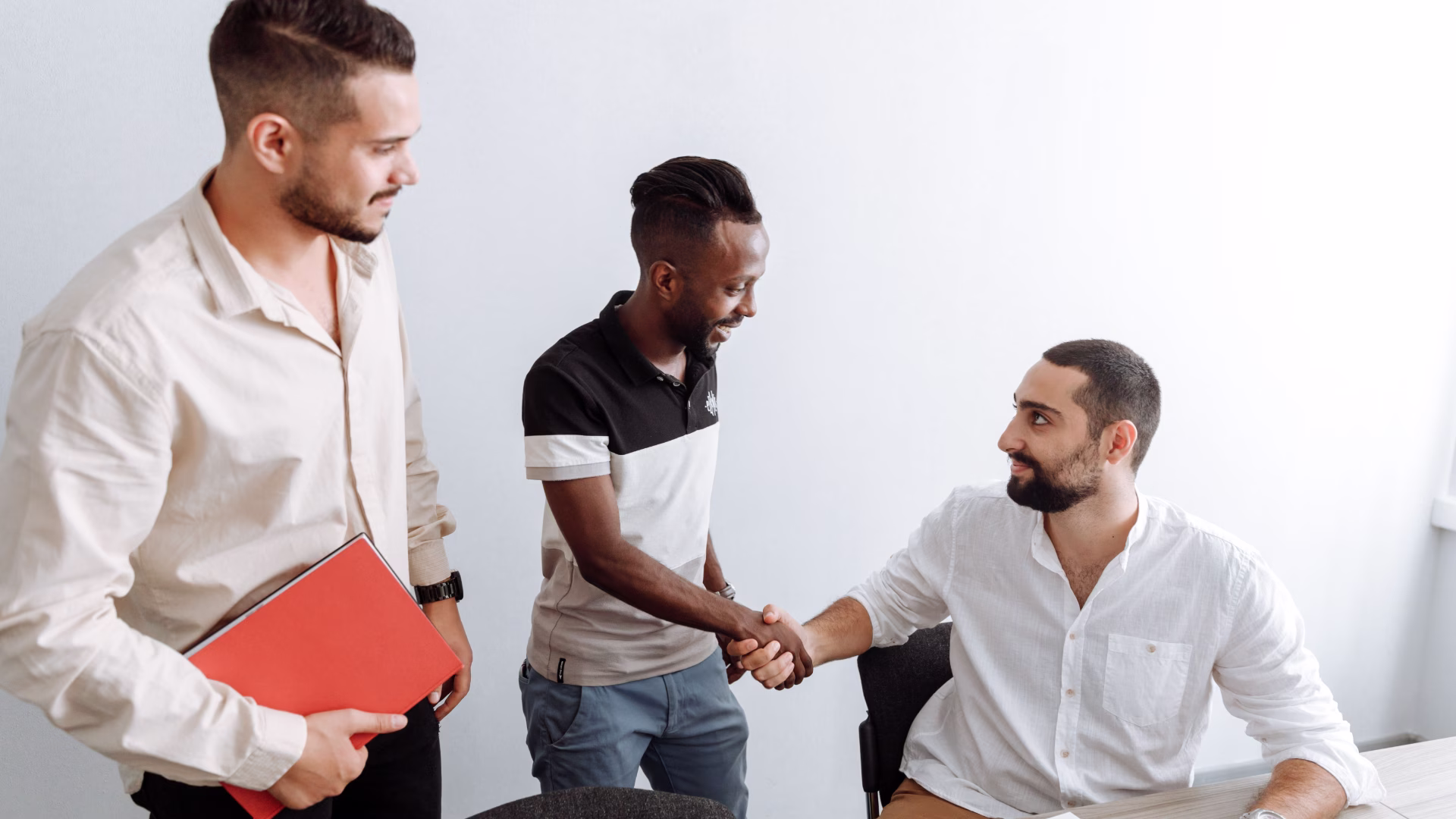 a person sitting down talking to two people standing up smiling