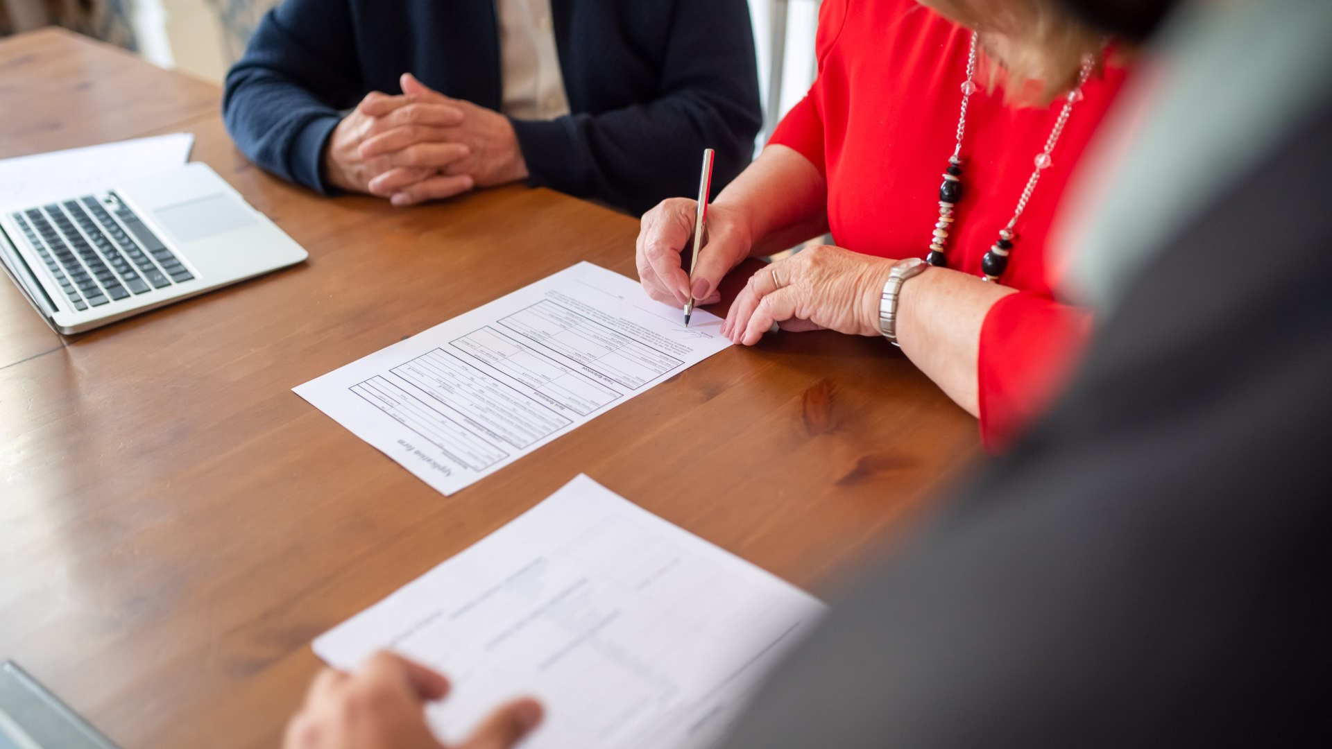 Contractor and client signing a document sitting at a table