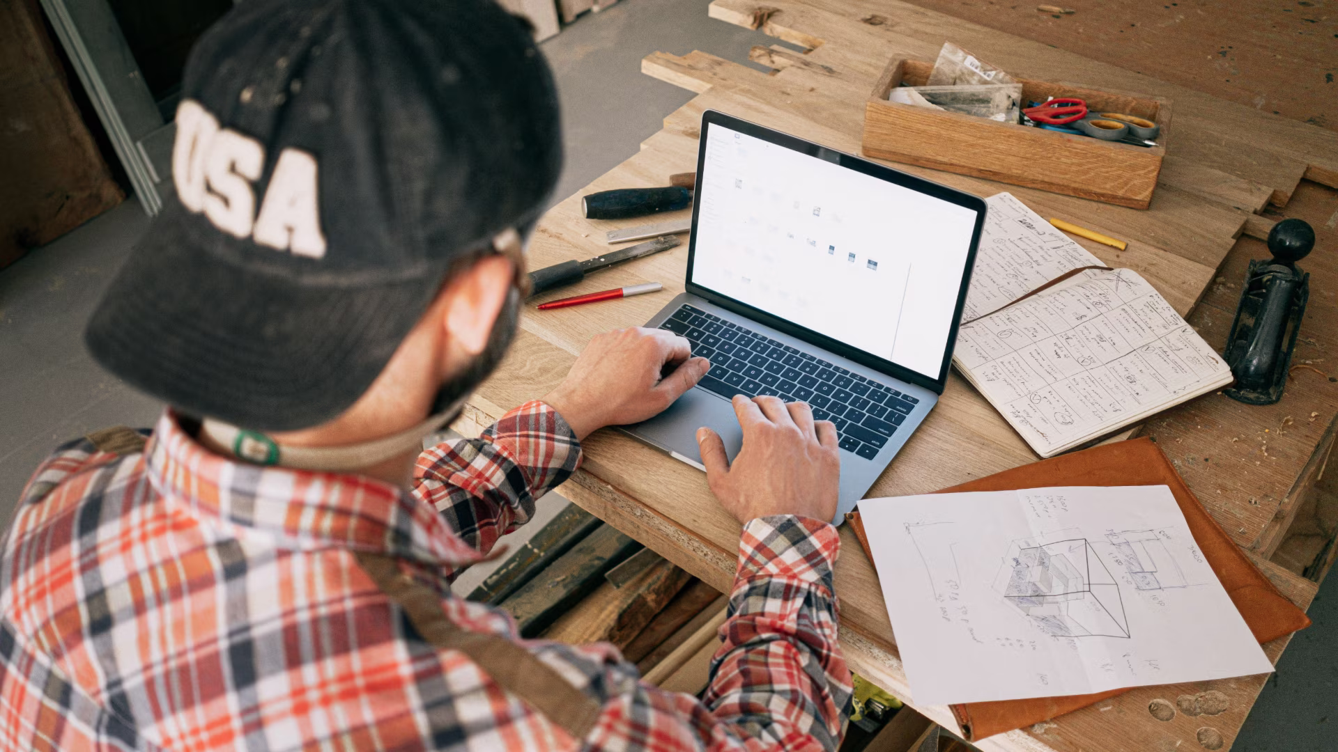 A contractor sitting at a workbench with a laptop logging into a vendor portal